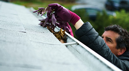 Man clearing leaves out of roof guttering