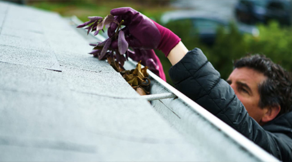Man clearing house gutters